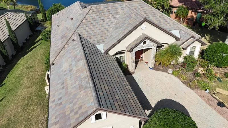 Aerial view of a finished blended flat-tile roof with a standing-seam metal accent section on a Southwest Florida lakefront home